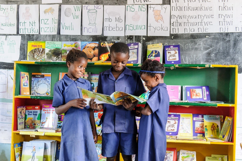 Hamubwatu Primary pupils giggling and reading by their classroom library